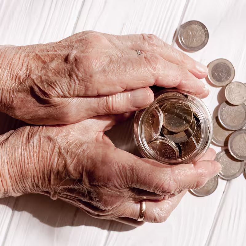 Manos sosteniendo un frasco lleno de monedas